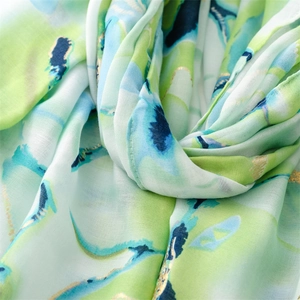 Close-up of lightweight linen-touch scarf with green ink wash pattern and gold foil accents
