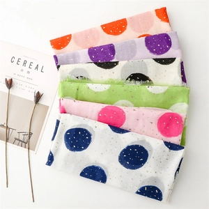 Detailed shot of layered cotton linen scarves with gold foil polka dots in vibrant colors
