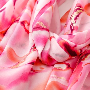 Macro detail of pink floral chiffon scarf featuring gold foil printing and artistic texture