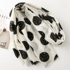 Macro detail of beige cotton linen scarf with gold-stamped polka dots and frayed edges