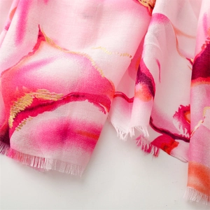 Detail of pink cotton scarf featuring gold foil floral print and frayed edges