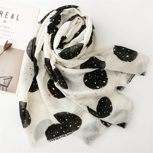 Detail of cream scarf with black polka dots, gold foil finish, and frayed edges