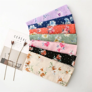 Detailed flat lay of colorful cotton linen scarves with daisy patterns and fringe edges