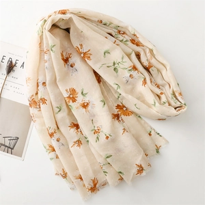 Detail of cream cotton linen scarf featuring orange daisy print and frayed edges