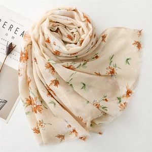 Detail of beige cotton-linen scarf with orange daisy floral print and frayed edges