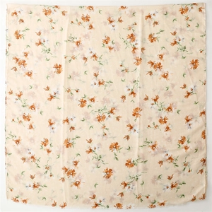 Detail of floral linen scarf with gold foil dots and fringe edges on cream fabric