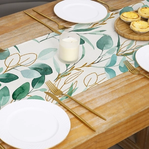 Polyester table runner with green leaf and gold vein pattern on wooden dining table