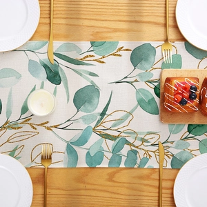 Polyester table runner with green eucalyptus and gold leaf print on wooden table