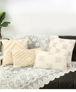 Detail of bohemian tufted throw pillows with geometric patterns and fringe on leather sofa