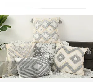 Macro detail of geometric tufted patterns and gray tassels on cream cushion covers