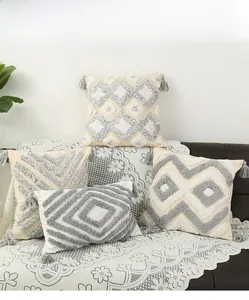 Detail of bohemian tufted geometric pattern and grey tassels on square pillow covers
