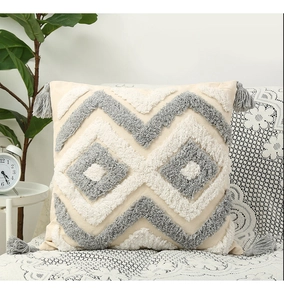 Close-up of tufted geometric texture and grey tassels on a boho throw pillow case
