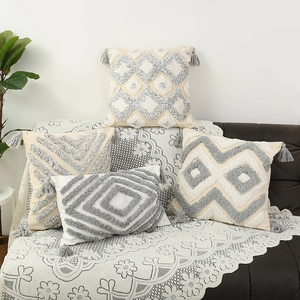 Nordic tufted geometric pillow covers with grey tassels on a black leather sofa