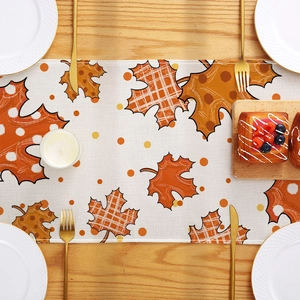 Autumn harvest table runner featuring maple leaf prints on a textured rustic wood table