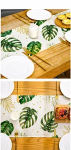 Détail d'un chemin de table imprimé monstera sur une table en bois avec de la vaisselle