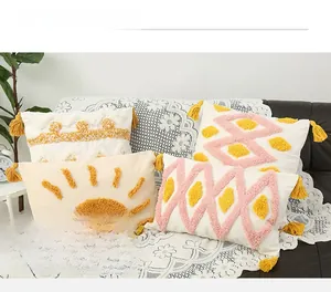Detail of bohemian tufted cushion covers with yellow tassels and geometric patterns