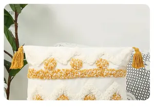 Close-up of bohemian tufted pillow cover with yellow geometric embroidery and tassels