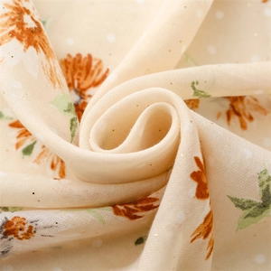 Detailed macro view of beige linen-touch scarf featuring orange sunflower patterns and gold sequins