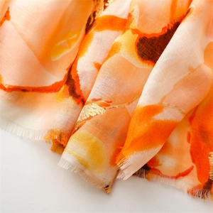Close-up of linen-feel scarf with gold foil floral pattern and fringed edges