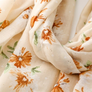 Detailed texture of cotton linen scarf with gold foil dots and orange floral pattern