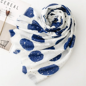 Detail of white cotton linen scarf with blue polka dots, gold foil, and frayed edges