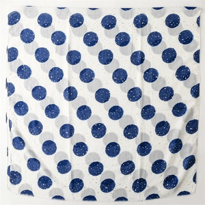 Detailed texture of white cotton linen scarf with blue polka dots and gold foil accents