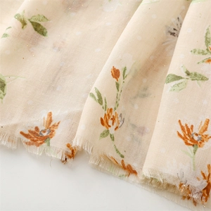 Macro view of light beige cotton-linen scarf with floral pattern and gold foil dots
