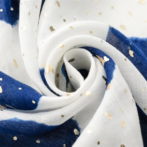 Close-up of blue and white linen-feel scarf with gold foil dots in artistic swirl