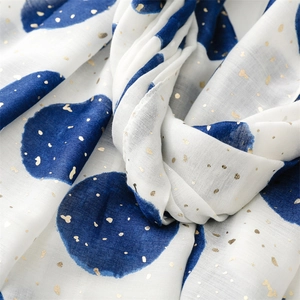 Macro view of white scarf featuring blue polka dots and sparkling gold foil texture