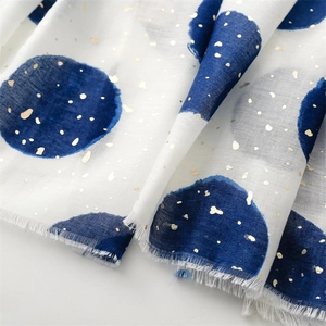 Detail of cotton linen scarf with blue dots, gold foil finish, and frayed edges