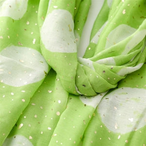 Macro detail of green cotton linen scarf with white polka dots and gold foil printing