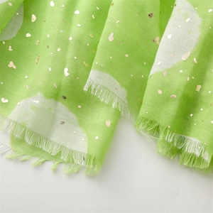 Detail of light green scarf showing golden foil dots and delicate fringe edges