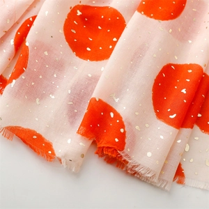 Detail of peach cotton scarf featuring orange polka dots and decorative gold foil patterns