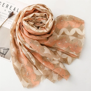 Detail of warm orange wave pattern scarf with metallic gold threads and fringe edges