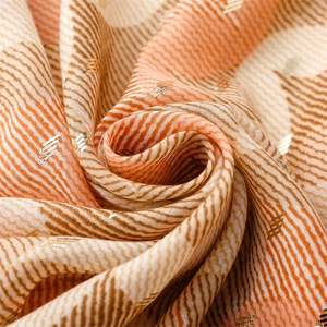 Macro detail of geometric gold foil embroidery on soft orange and brown plaid cotton scarf