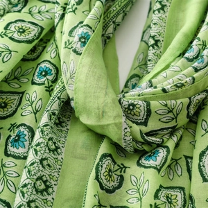 Détail d'une écharpe vert clair au toucher lin avec imprimé floral et franges fines