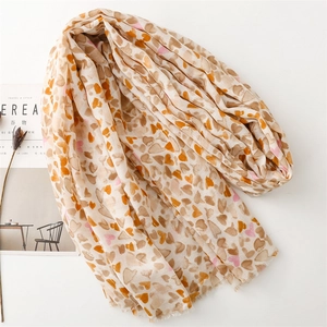 Détails d'une écharpe en lin beige ornée de motifs de cœurs orange et roses