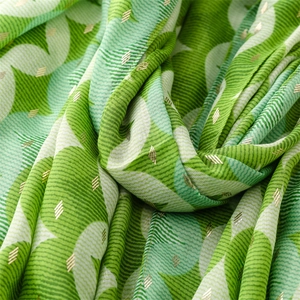 Detail of green scarf featuring abstract geometric patterns with gold foil texture accents
