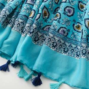 Détail d'une écharpe bleue à motif cachemire avec des glands délicats sur tissu en coton lin