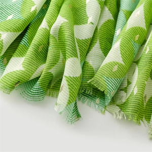 Detail of green geometric pattern scarf with gold foil accents and fringe edges