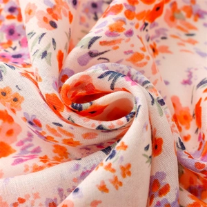 Détail d'une écharpe aspect coton-lin avec de petits motifs floraux orange et bleus