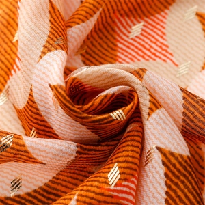 Macro shot of geometric jacquard fabric with gold accents and orange wave patterns