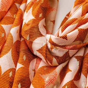 Detail of orange and white cotton linen scarf with geometric gold foil patterns