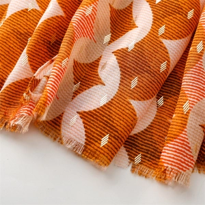 Detail of orange geometric scarf with gold foil accents and natural fringed edges