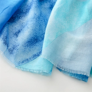 Close-up of blue gradient cotton linen scarf featuring delicate frayed edges and soft texture