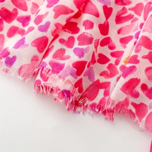 Détail d'une écharpe à imprimé cœurs roses avec bords effilochés en coton et lin