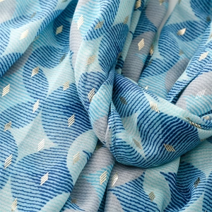Detailed macro of geometric blue scarf with gold foil accents and soft fabric texture