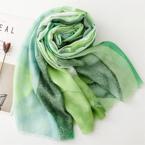 Detail shot of lightweight cotton linen scarf featuring green gradient watercolor print and raw edges