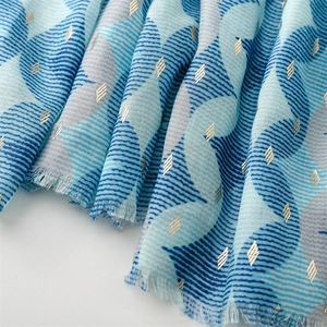 Detail of blue and grey wavy patterned scarf with gold foil accents and fringed edges