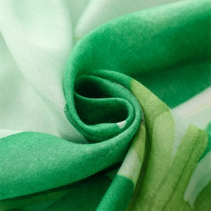 Macro detail of soft cotton linen scarf showing green tropical pattern and fabric texture